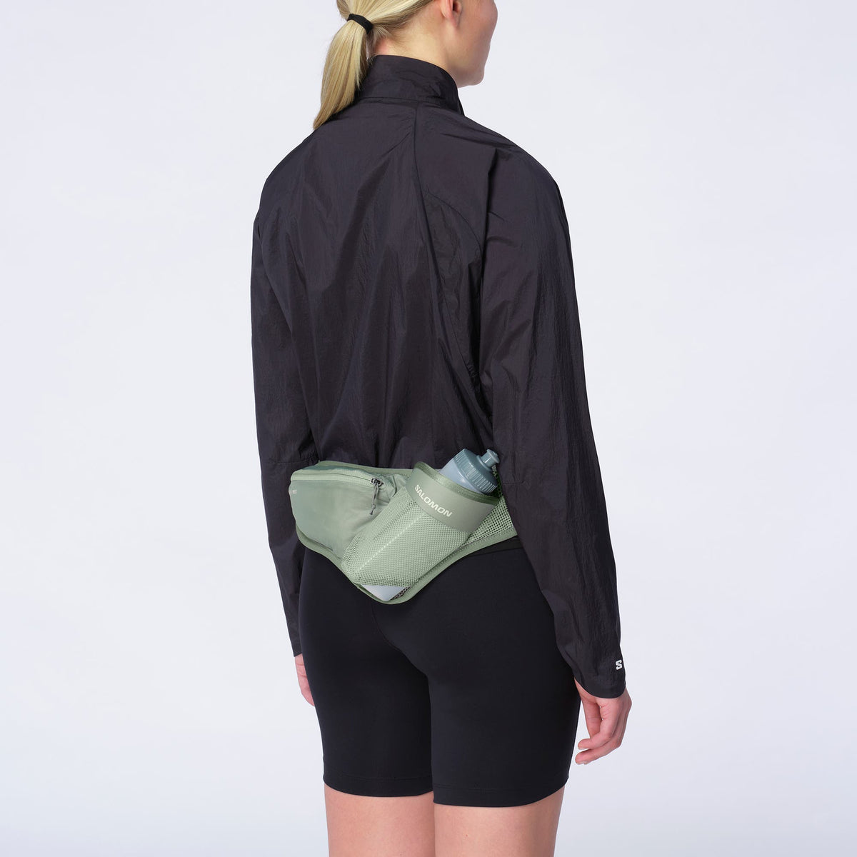 Woman wearing Salomon Active Belt 3D hydration waist pack in sage green while running