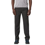Man wearing dark gray Patagonia convertible pants with hiking shoes on white background