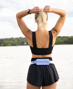 Female athlete wearing SPIbelt Monochromatic Pro Belt in Space Blue at waterfront