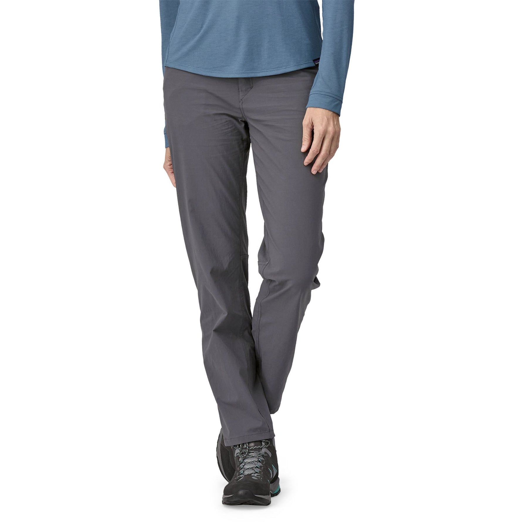 Woman wearing grey Patagonia Quandary pants with blue long-sleeve top and hiking shoes