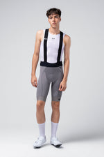 Male cyclist wearing gray Gobik Absolute 7.0 bib shorts with white jersey and socks