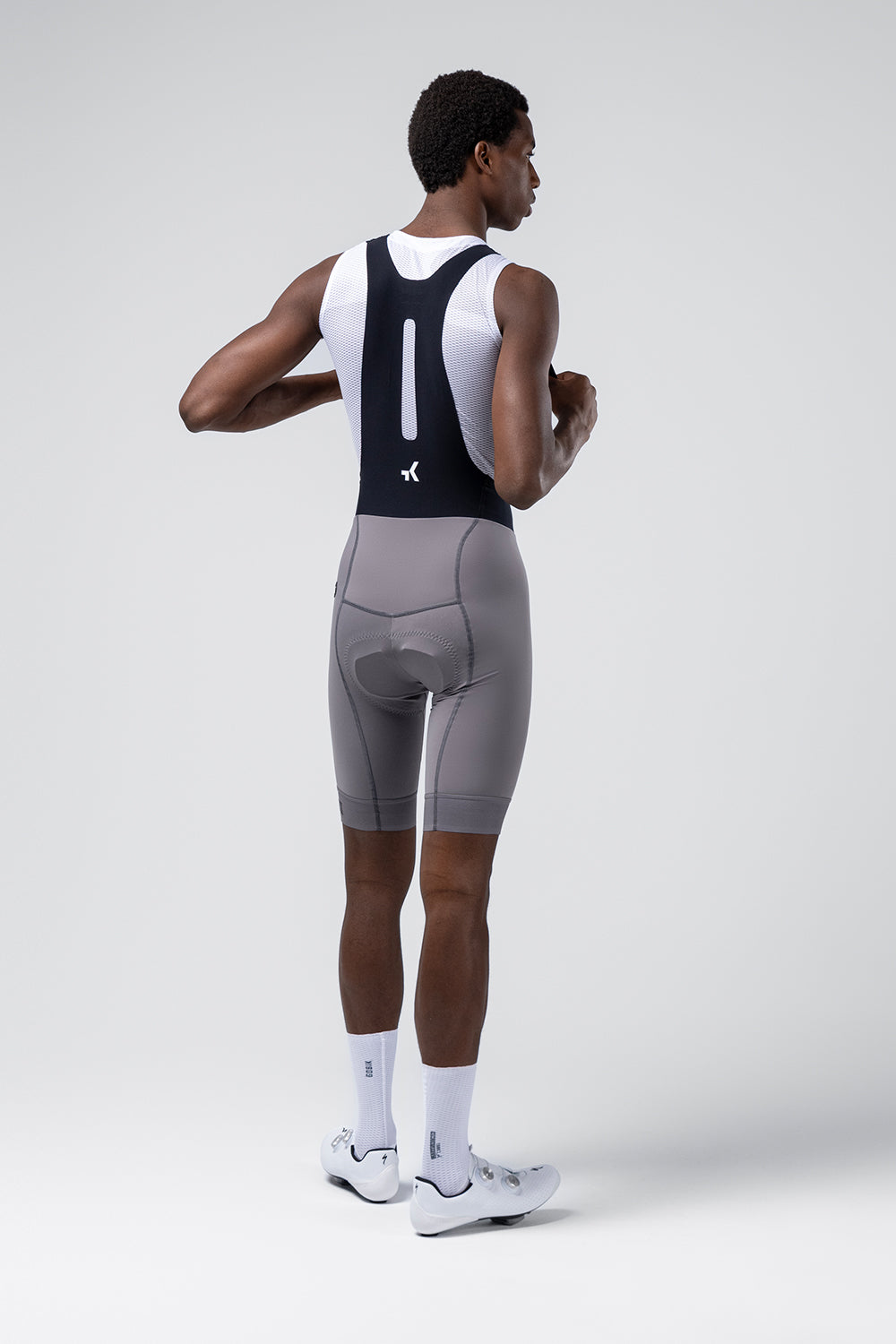 Gobik Absolute Compact 7.0 bib shorts in Kettle gray worn by male cyclist, rear view
