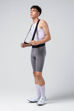 Male cyclist wearing gray Gobik X Bib Short with white tank top and cycling shoes