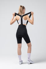 Woman wearing black Gobik X bib shorts with shoulder straps, rear view