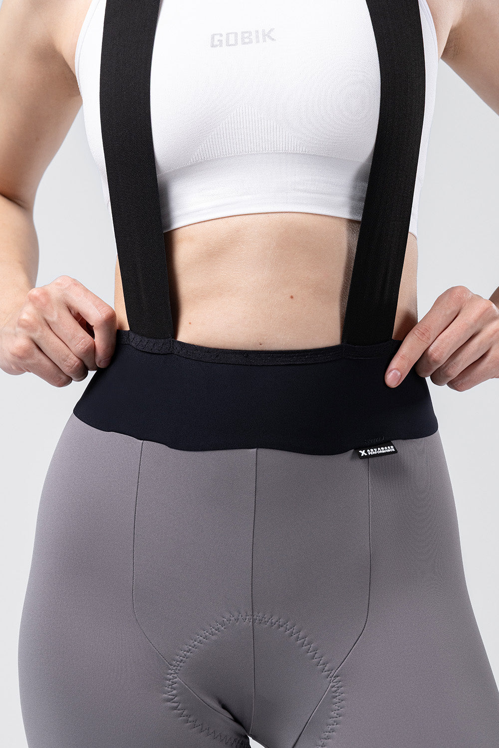 Gobik X Women's bib shorts in gray with black suspenders and white sports bra
