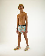 Man wearing ChicknLegs Flying Pigs split shorts in turquoise with pink pig pattern