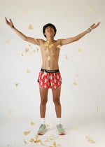 Man wearing red Chicknlegs burrito pattern shorts with arms raised celebrating