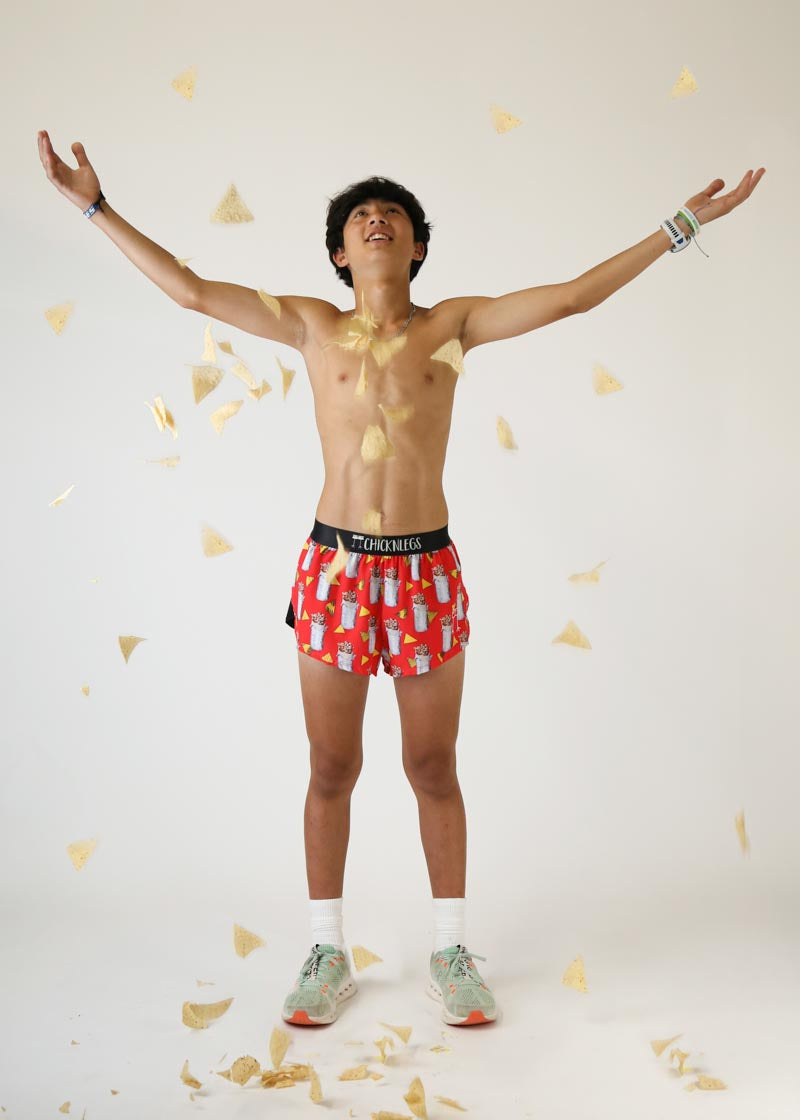 Young man wearing red Chicknlegs burrito print shorts with arms raised in celebration