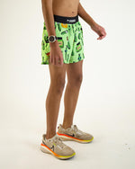 Man wearing bright green Chicknlegs shorts with pickle print pattern and Nike sneakers