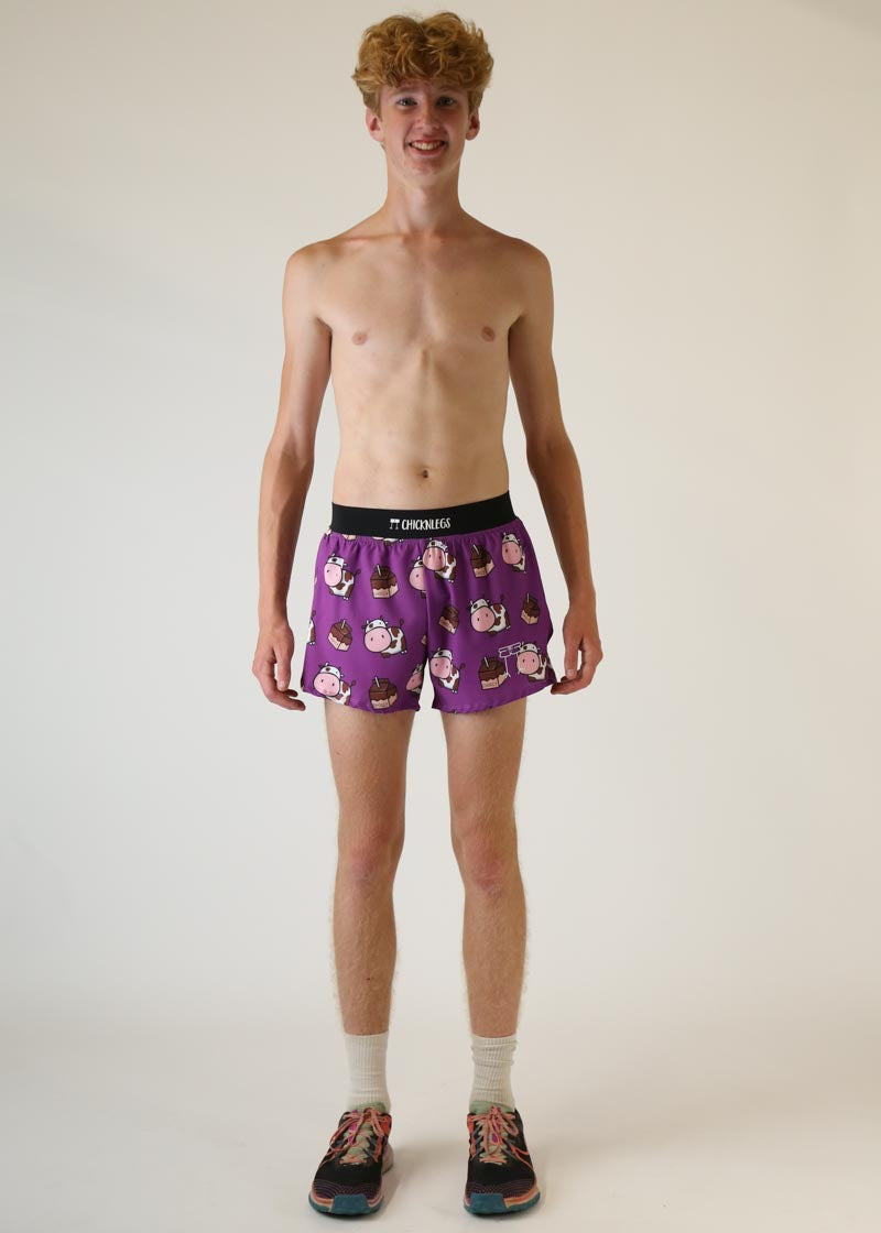 Man wearing purple ChicknLegs shorts with chocolate cow pattern against white background