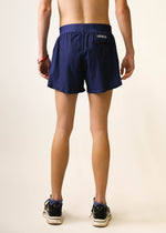 Back view of ChicknLegs navy blue 4-inch half split running shorts on male model