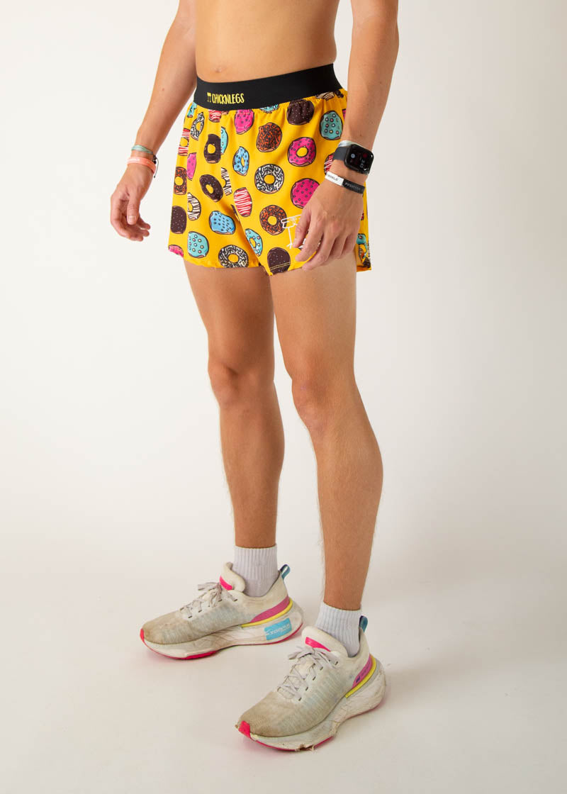 ChicknLegs men's yellow running shorts with colorful donut pattern, modeled on white background