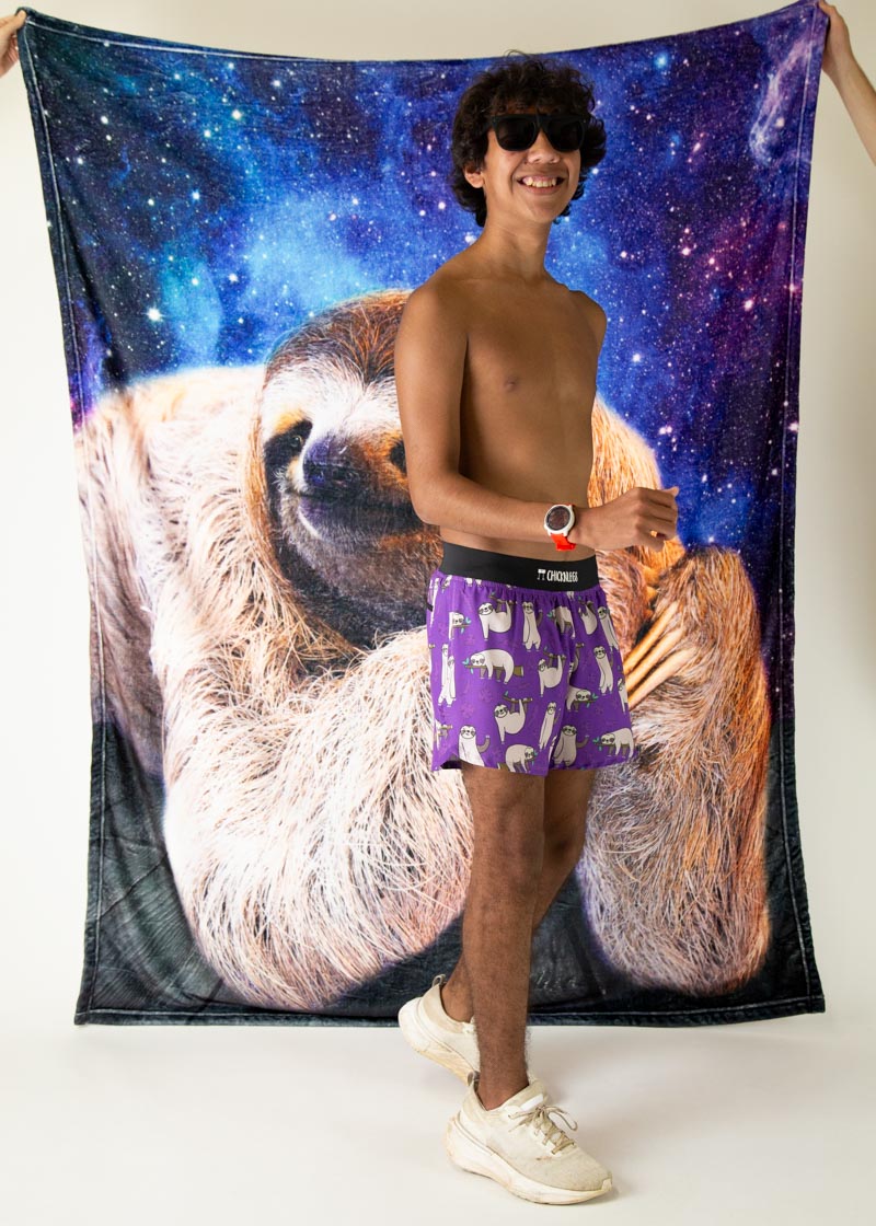 Man wearing purple ChicknLegs boxer shorts with sloth pattern against galaxy backdrop