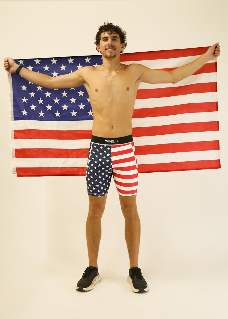 Man wearing ChicknLegs USA flag pattern half tights holding American flag