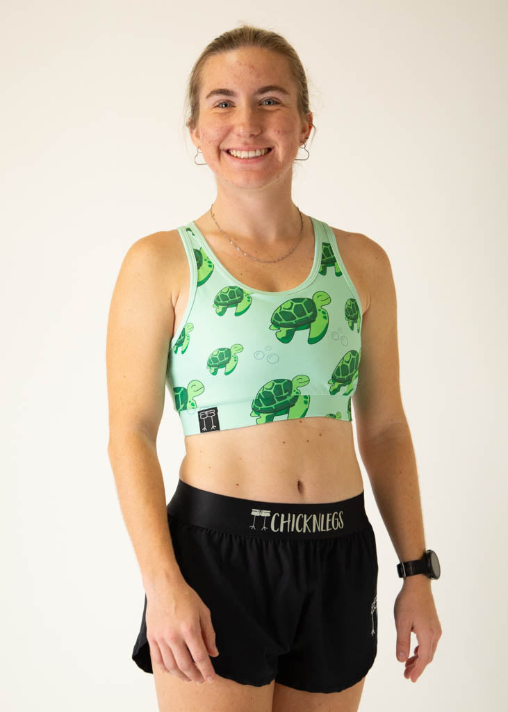 Woman wearing ChicknLegs sea turtle pattern sports bra in mint green with black shorts