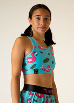 Woman wearing ChicknLegs turquoise sports bra with pink flamingo and tropical leaf print