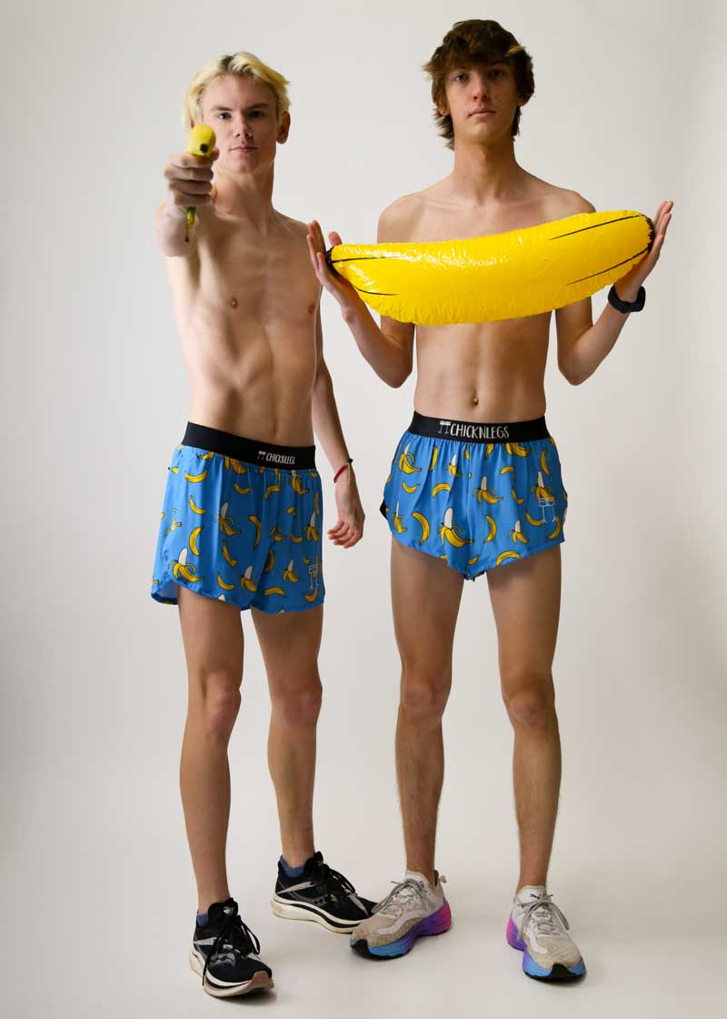 Two male models wearing ChicknLegs blue banana print 4-inch split running shorts