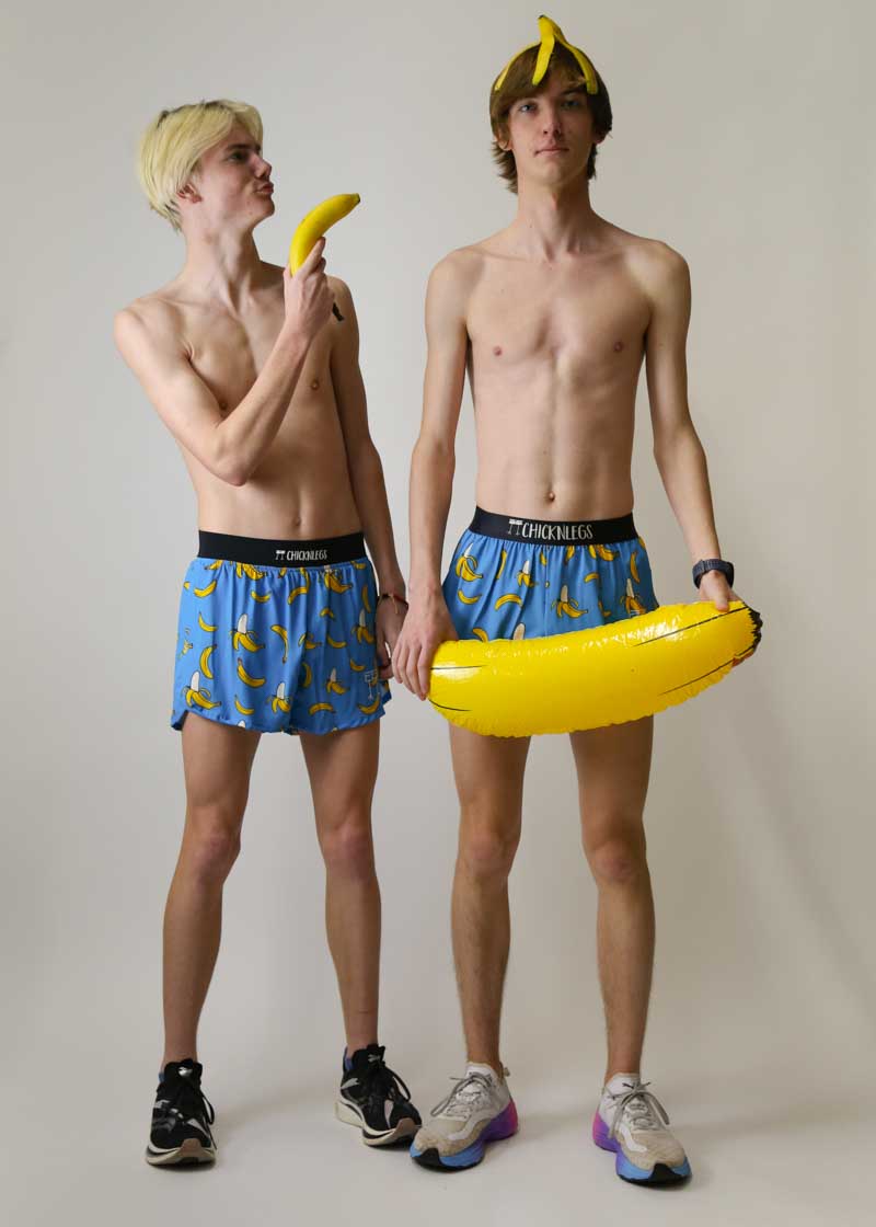 Two male models wearing ChicknLegs banana print split running shorts with banana props
