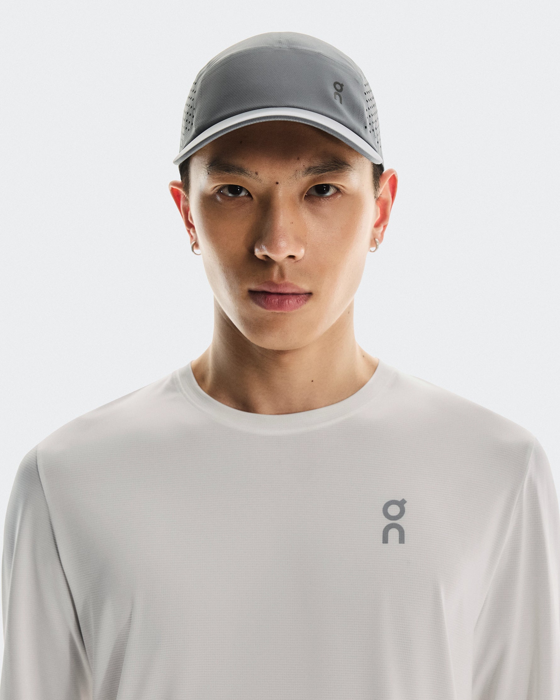 Asian male model wearing grey On Lightweight Unisex Cap and white athletic shirt