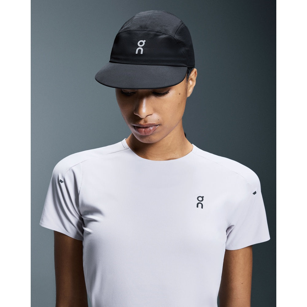 Woman wearing On Performance Cap in black with white logo, paired with white On t-shirt