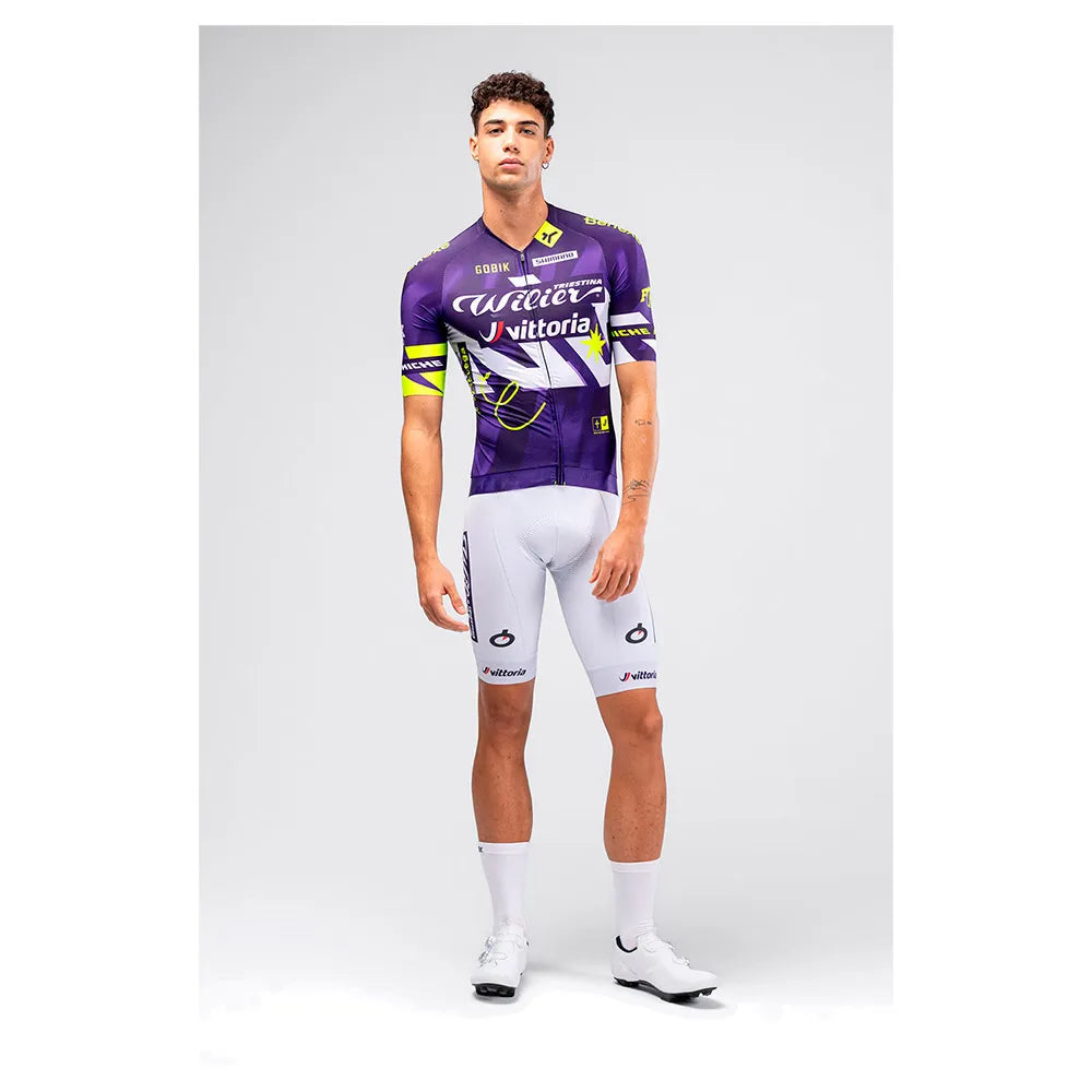 Male cyclist modeling Gobik CX Pro 4.0 violet jersey with white bib shorts full body front view