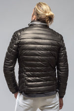 Man wearing black quilted puffer jacket shown from behind on gray background