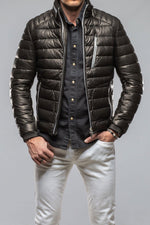 Man wearing black quilted puffer jacket with silver zippers over dark shirt and white pants
