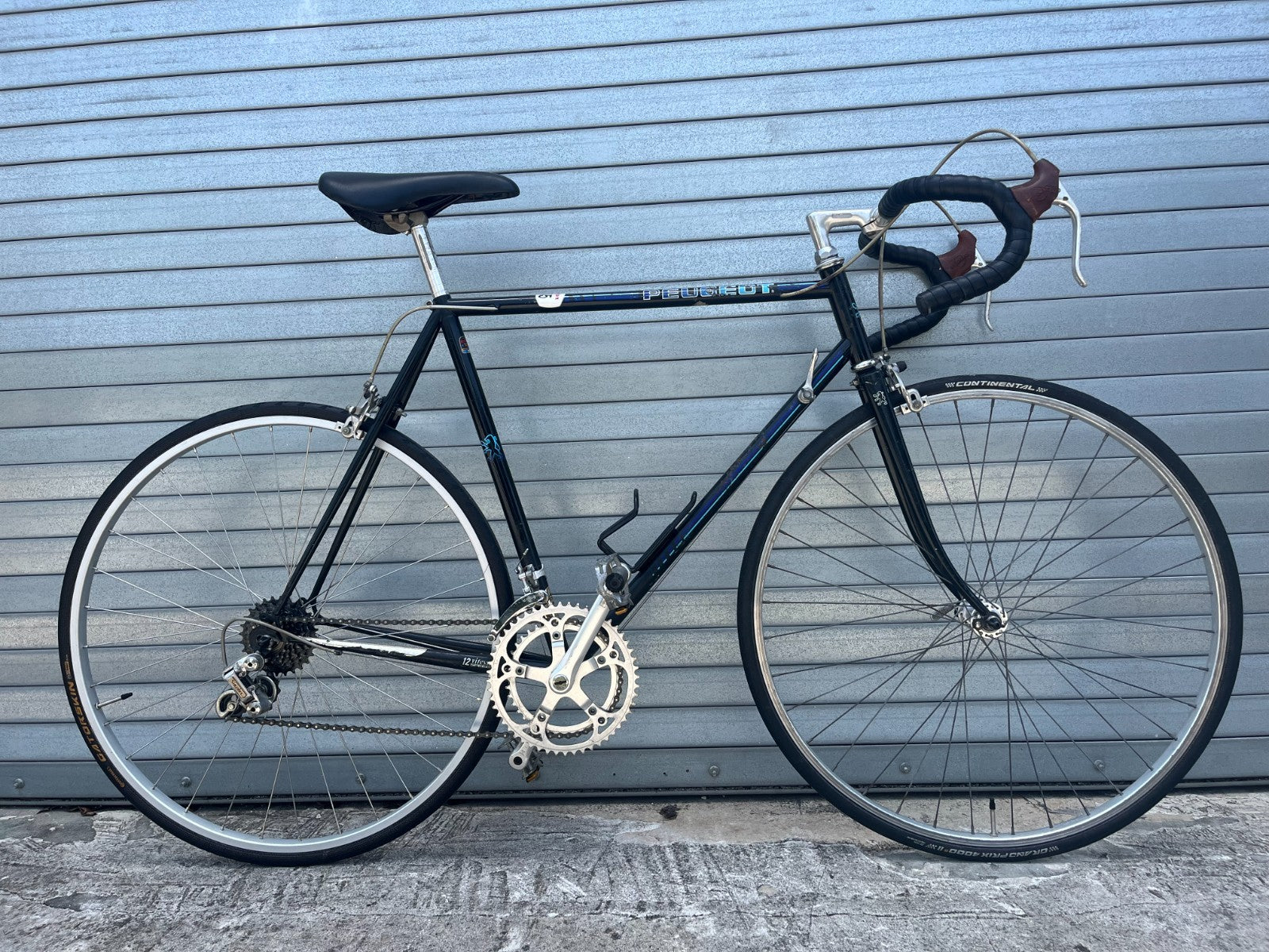 Classic drop handlebars with newer black bar tape on vintage Peugeot road bike