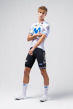 Model wearing white Gobik cycling jersey with blue Movistar team logo and black shorts