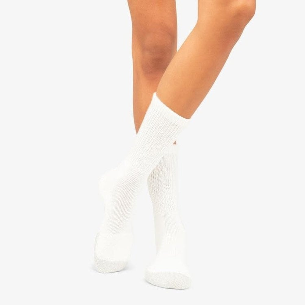 Thorlos white thick cushion crew socks worn on female legs against clean background
