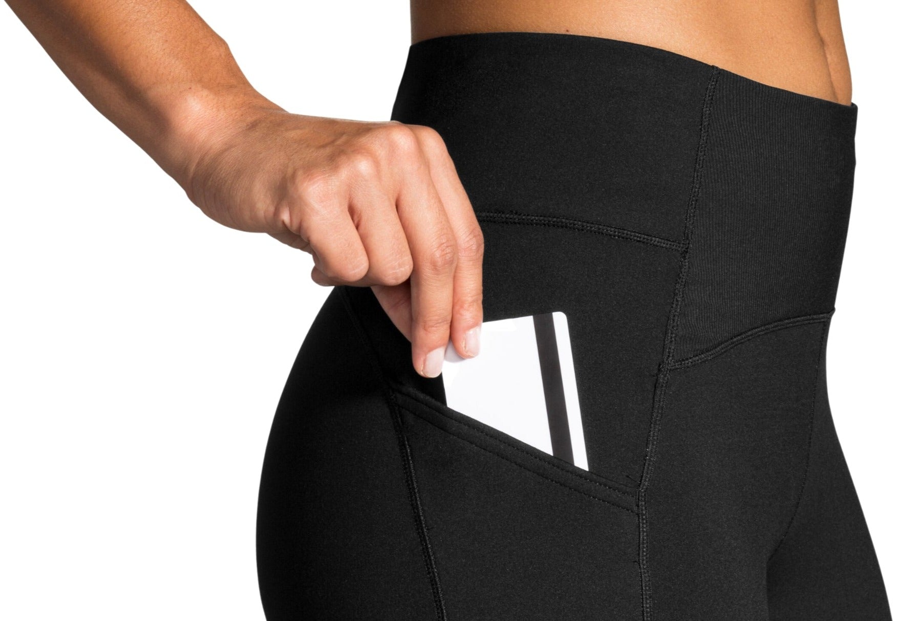 Woman wearing black thermal tights with side pocket holding white phone